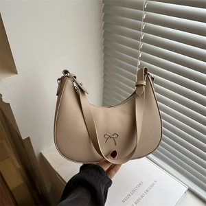 Chic beige half-moon hobo bag with a silver bow detail and wide shoulder strap