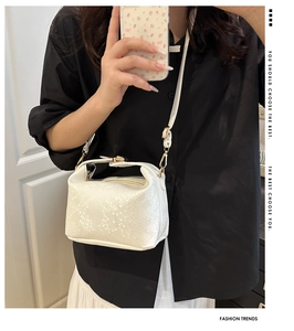 Detail of white snakeskin pattern crossbody bag with golden metal zipper and hardware