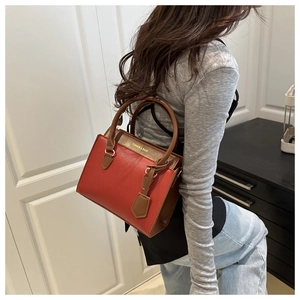 Detail of red and brown patchwork leather tote bag with elegant gold foil lettering