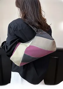Makrodetail der farbblockierten Canvas-Hobo-Tasche mit Vintage-Stoffstruktur und Lederriemen