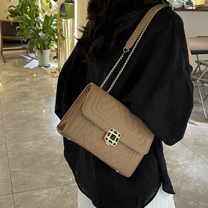 Khaki quilted crossbody bag with gold square buckle and chain strap on a model