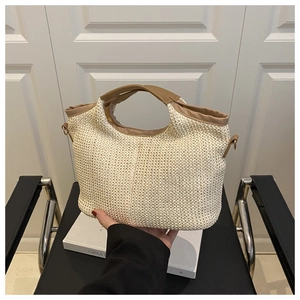Détail du sac tressé crème avec bordure en cuir marron et crochets métalliques