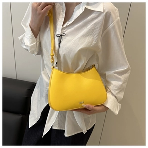 Detail of a bright yellow crescent shoulder bag with golden logo and adjustable strap