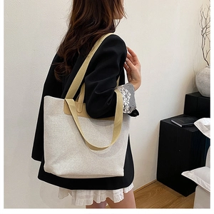 Detail of large canvas tote bag with leather handles shown in a minimalist interior setting