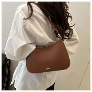 Detail of the brown leather shoulder bag with a gold metal logo and adjustable strap