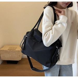 Detail einer schwarzen Nylon-Tasche mit mehreren Reißverschlussfächern und Schultergurt