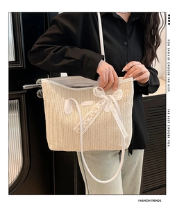 Détail d'un sac cabas en paille tissée avec nœud en dentelle et anses en cuir
