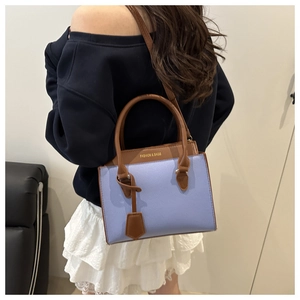 Detail showing contrast blue and brown crossbody bag with gold text branding