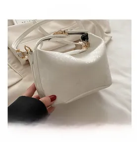Detail of white faux python embossed texture and golden hardware on small square bag