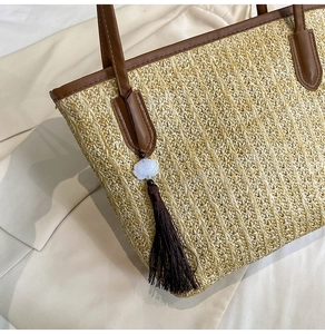 Detailed straw tote bag texture with brown leather trim and elegant flower tassel charm