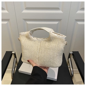 Détail d'un sac cabas tissé avec poignées en cuir et anneaux métalliques dorés élégants