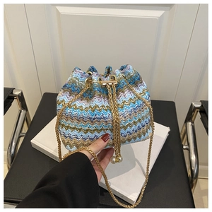 Close-up of woven bucket bag with colorful wavy patterns and pearl drawstring detail