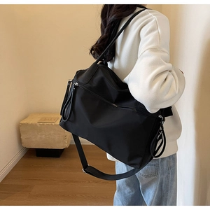 Detail der schwarzen Nylontasche mit Ledergriffen in minimalistischem Wohnambiente