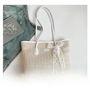Détail du sac cabas en paille avec nœud en dentelle blanche et bandoulière en cuir