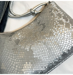 Close-up of silver snakeskin texture and knotted strap on a chic shoulder bag