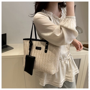 Detail of woven straw tote bag with black leather straps and a matching mini coin purse