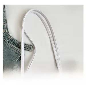 Détail de la couture haute densité sur les poignées en cuir blanc du sac cabas tressé