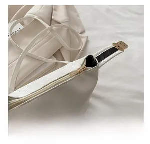 Close-up of smooth gold zipper and snakeskin embossed texture on cream shoulder bag