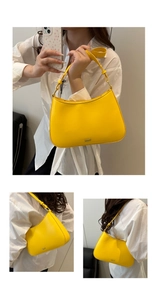 Detail view of a bright yellow half-moon hobo bag with sleek metal logo and shoulder strap