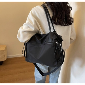 Detailansicht einer großen schwarzen Nylon-Einkaufstasche, getragen von einem Modell