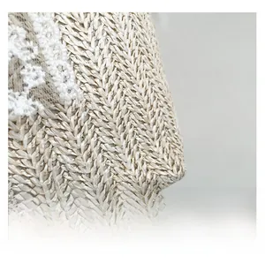 Détail de la texture en paille tressée avec dentelle florale blanche sur un sac