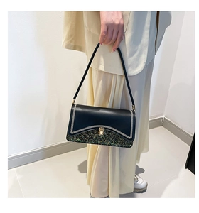 Detail of black leather handbag featuring contrast sequins and gold twist lock closure