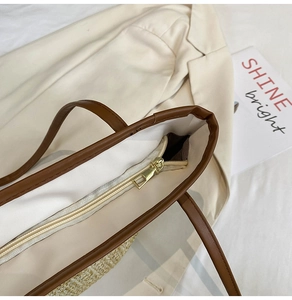 Detail of woven straw tote with brown leather trim and secure golden metal zipper closure