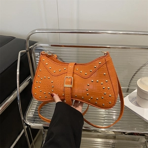 Sac croissant orange à texture crocodile et détails de rivets métalliques dorés