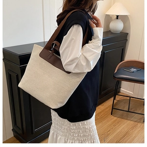Detailed view of the large linen tote bag with brown leather handles worn by a model
