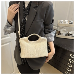 Détail d'un sac cabas tissé crème montrant la texture fine et l'anse en cuir sur mannequin