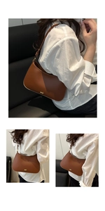 Detail of a brown leather crescent underarm bag with adjustable strap and gold logo