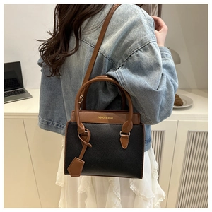 Detail of contrast leather shoulder bag featuring black pebble grain and brown handles