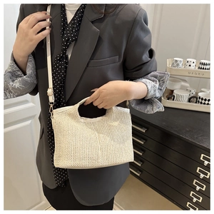 Détail du sac cabas en paille tissé main avec texture élégante et bandoulière en cuir