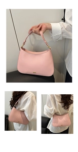 Detail view of pink underarm bag with adjustable strap and golden logo