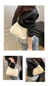 Detail of cream white crescent underarm bag with gold metal logo and adjustable strap