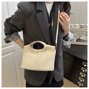 Photo lifestyle d'un sac cabas en paille tressée beige avec bordure en cuir en bandoulière