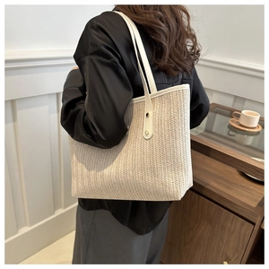 Detailed close-up of large straw tote bag with V-shaped weave and white leather straps