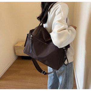 Braune Nylon-Tragetasche an der Schulter in minimalistischer Innenumgebung gezeigt