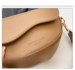 Detail shot of camel leather saddle bag showing fine texture and embossed fashion text