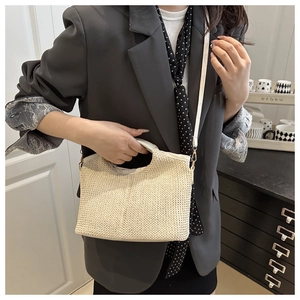 Détail du sac cabas en paille tressée avec poignées en cuir et bandoulière amovible