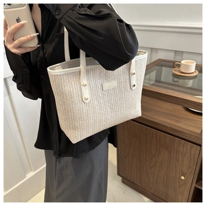 Detail of hand-woven straw tote with white leather strap in minimalist lifestyle setting