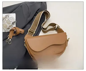 Detail of caramel saddle bag with wave-edge flap and interchangeable wide fabric straps