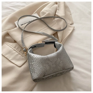 Close-up of gray snakeskin embossed shoulder bag with gold metal clasp on blazer