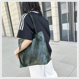 Macro detail of dark green vintage oil-wax leather tote bag with natural texture finish