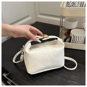 Detail of white snakeskin texture on mini square bag with golden metallic lock and handle