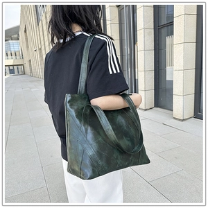Detail of vintage dark green tote bag featuring unique patchwork leather texture