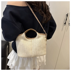 Détail du sac cabas en paille tissé main avec lanières en cuir sur un mannequin