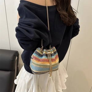 Colorful woven bucket bag with gold chain strap and pearl drawstring on model