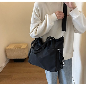 Detail einer schwarzen Nylon-Tasche mit robusten Doppelgriffen und verstellbarem Gurt