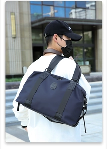 Dettaglio borsa da viaggio blu navy impermeabile con logo in pelle e tracolla regolabile